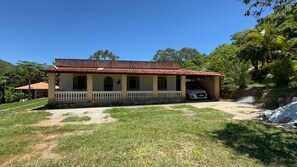 Uma casa de dois andares com varanda coberta e um carro estacionado na entrada.