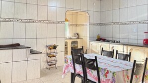 Una cocina con paredes de azulejos, una mesa de comedor con sillas, una cesta de frutas y una estufa.