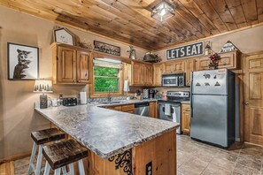 Eine Küche mit Holzausstattung, einer Granit Arbeitsplatte, einem Edelstahl Kühlschrank und einem Schild mit der Aufschrift 'LET'S EAT'.