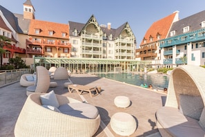 A rooftop pool area with wicker lounge chairs and a glass balustrade. - Premium Deauville Spa Apartment for 8 (Deauville)