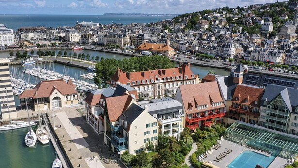 A coastal cityscape with a marina, historic buildings, and a swimming pool area. - Premium Deauville Spa Apartment for 8 (Deauville)