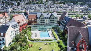 A hotel with a swimming pool, surrounded by lush greenery and traditional architecture. - Premium Deauville Spa Apartment for 8 (Deauville)