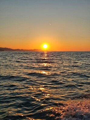 A sunset over a body of water with a distant shoreline.
