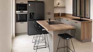 A modern kitchen with a central island, bar stools, a built-in oven, a refrigerator, and a sink. - Fully renovated villa in Provence, with large pool and spectacular valley view (Bargemon)