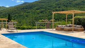 A pool with a mountain backdrop, a covered seating area, and a chair. - Fully renovated villa in Provence, with large pool and spectacular valley view (Bargemon)
