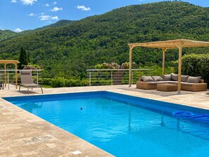 Ein Pool mit Bergblick, einem überdachten Sitzbereich und einem Stuhl.