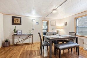 A dining area with a wooden table, chairs, and a bench. There is a small side table with a plant and a framed picture. The room has wooden flooring and a ceiling with recessed lighting. - Dog friendly(with dog fee),Close to Downtown,Historic District, (Galena)