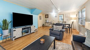 A living room with a flat-screen TV, a sofa, a dining table, and a chair. - Dog friendly(with dog fee),Close to Downtown,Historic District, (Galena)