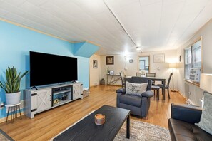 A living room with a flat-screen TV, a sofa, a dining table, and a chair. - Dog friendly(with dog fee),Close to Downtown,Historic District, (Galena)