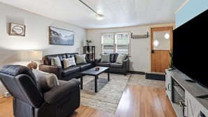 A living room with a sofa, armchair, coffee table, and a TV stand. - Dog friendly(with dog fee),Close to Downtown,Historic District, (Galena)