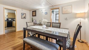 A dining area with a table, chairs, a bench, a lamp, and a kitchen in the background. - Dog friendly(with dog fee),Close to Downtown,Historic District, (Galena)