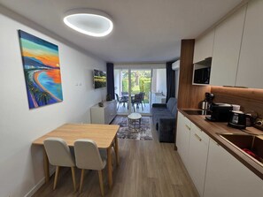 A modern kitchen with a dining area, a TV mounted above the counter, and a painting on the wall. - L'Ecrin Lolita Cannes - Exceptional (Cannes)