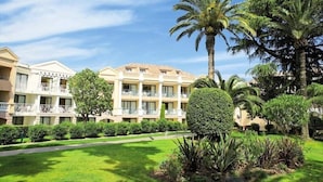 A hotel with multiple balconies, lush greenery, and palm trees. - L'Ecrin Lolita Cannes - Exceptional (Cannes)