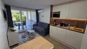 A modern apartment with a dining area, a sofa, a kitchen with a built-in microwave, and a sliding glass door to a balcony. - L'Ecrin Lolita Cannes - Exceptional (Cannes)
