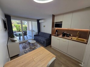 A modern apartment with a dining area, a sofa, a kitchen with a built-in microwave, and a sliding glass door to a balcony. - L'Ecrin Lolita Cannes - Exceptional (Cannes)