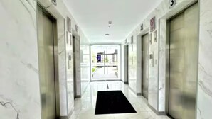 A hallway with marble walls and floors, numbered doors, and a black mat at the entrance. - Modern Apt in Lince Just Steps from San Isidro (Lince)