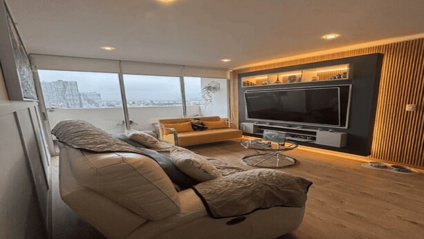 A modern living room with a large flat-screen TV, a sofa, and a coffee table. - Modern Apt in Lince Just Steps from San Isidro (Lince)