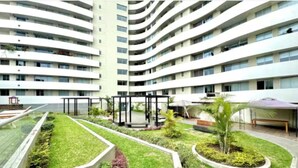 A multi-story hotel with a central courtyard featuring a glass railing, greenery, and a seating area. - Modern Apt in Lince Just Steps from San Isidro (Lince)