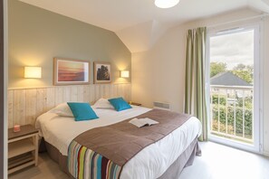 Quarto com cama grande, duas luminárias de cabeceira, janela com cortinas e vista para o exterior.
