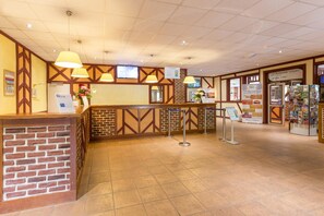 Ett receptionsomr åde med en bardisk i tegel, hängande lampor och informationsskyltar.