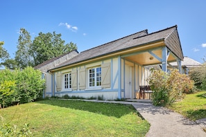 Ett tvåvåningshus med en inglasad veranda och en liten trädgård.
