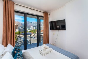 Ein Hotelzimmer mit Bett, Wandfernseher und großem Fenster mit Vorhängen.