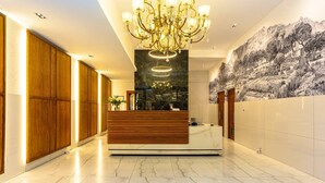 A hotel lobby with a reception desk, wooden paneling, a chandelier, and a mural on the wall. - Mountain Views 2BR Furnished De Waterkant (Cape Town)