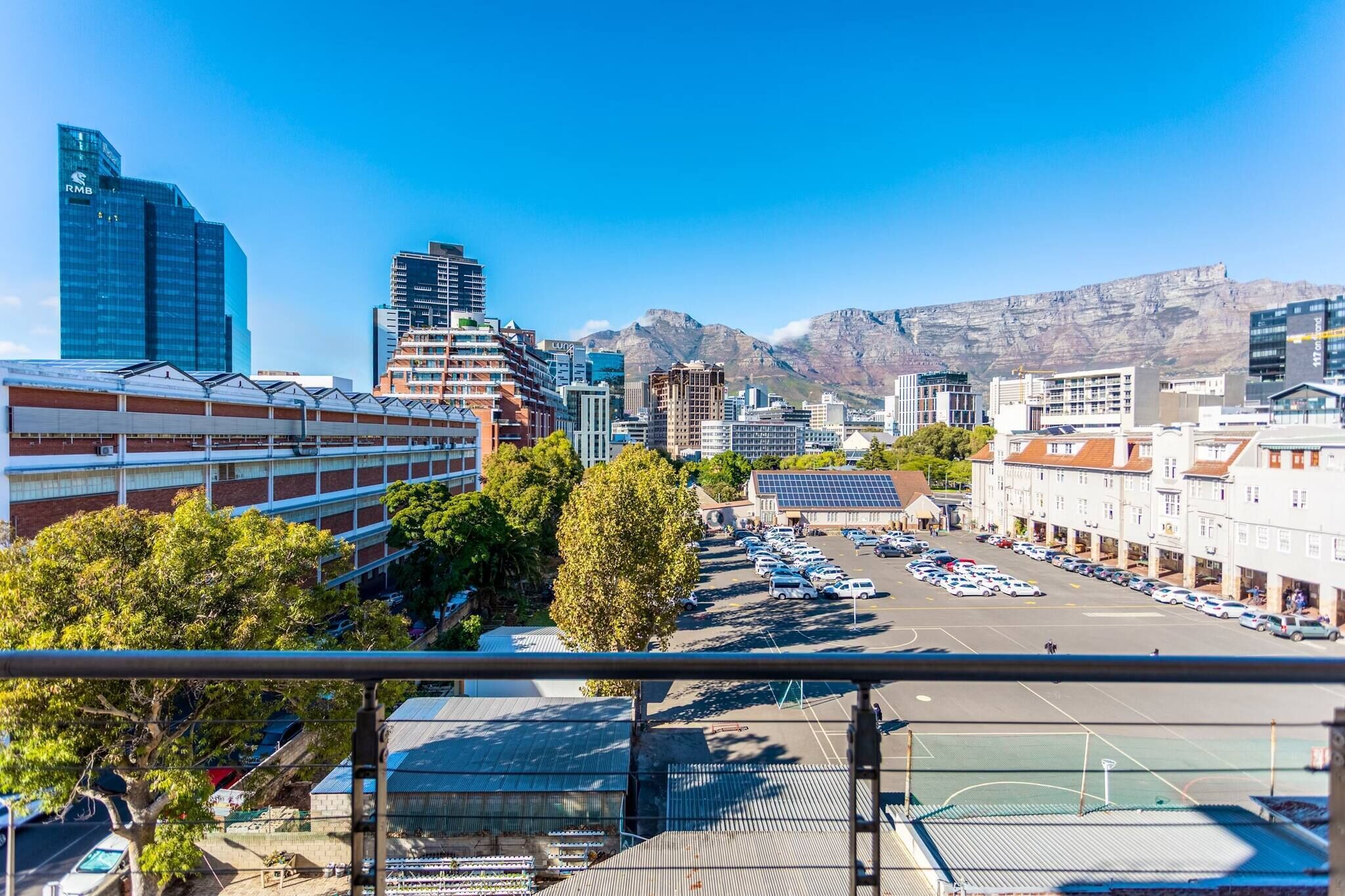 A cityscape with modern buildings, a parking lot, and a mountain in the background.