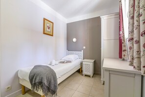 A bedroom with a bed, bedside table, nightstand, and a wall clock. - Ardeche Holiday Apartment for 4 (Grospierres)