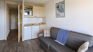 Un espacio habitable compacto con kitchenette, un sofá y una zona de comedor.
