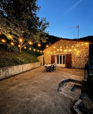A stone building with a patio, outdoor seating, and string lights.
