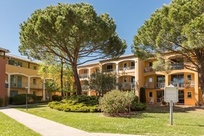 A multi-story building with balconies, a well-maintained lawn, and a clear sky. - Chic Riverfront Stay With Balcony (Mandelieu-La-Napoule)