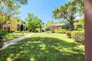 Un patio con un sendero, rodeado de edificios con balcones y vegetación.