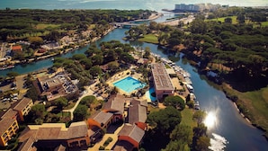 An aerial view of a resort with a swimming pool, marina, and surrounding greenery. - Chic Riverfront Stay With Balcony (Mandelieu-La-Napoule)
