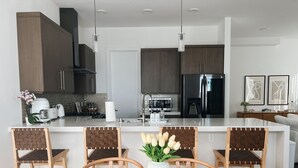 Une cuisine moderne avec des meubles en bois foncé, des appareils électroménagers en acier inoxydable et un îlot central doté de sièges.