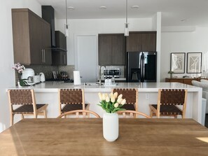 A modern kitchen with dark wood cabinets, stainless steel appliances, and a central island with seating. - Luxe Silver Lake Home: Rooftop Terrace, Hollywood Views, 3BR/3.5BA, 2-Car Garage (Los Angeles)