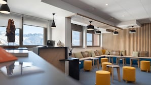 Ein modernes Interieur mit einer Rezeption, einer Sitzecke und großen Fenstern mit Blick auf die Berge.