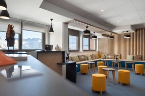 Ein modernes Interieur mit einer Rezeption, einer Sitzecke und großen Fenstern mit Blick auf die Berge.