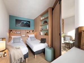 Una habitación de hotel moderna con dos camas, un escritorio, una computadora portátil y un ventanal grande.