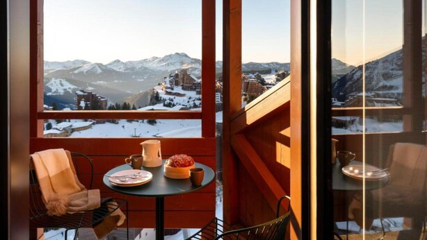 Ein Balkon mit Tisch für zwei Personen, einem Stuhl und Blick auf schneebedeckte Berge.