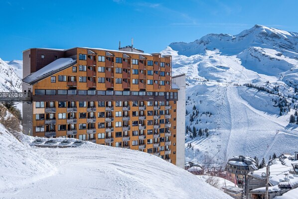 Un hotel de varios pisos con una pista de esquí al fondo.