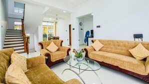 Ein Wohnzimmer mit zwei Sofas, einem Glastisch, einem Deckenventilator und einer Treppe.
