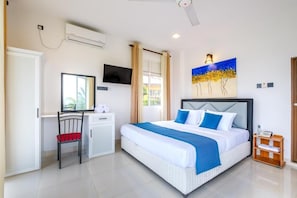 Un dormitorio con cama, escritorio, silla, televisor y un cuadro.