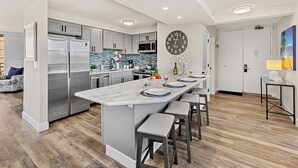 Una cocina moderna con una isla central, electrodomésticos de acero inoxidable y un reloj de pared grande.