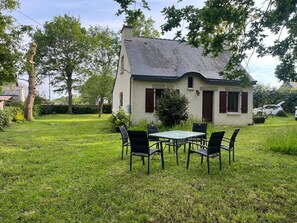 A house with a grassy yard, a table with chairs, and a car parked nearby. - Small house, 3km from the sea, on large enclosed garden (Moëlan-sur-Mer)