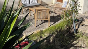 Una casa con un patio arredato con mobili in legno, una finestra con persiane e un lampione.