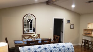 A dining area with a table, chairs, a vase with flowers, a window, and a kitchen area with stools. - Lake Bridgeport Waterfront Charming Home with Private Dock / Boat & Jet Ski lift (Bridgeport)