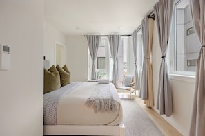 Ein Schlafzimmer mit einem Bett, einem Sessel und Vorhängen.