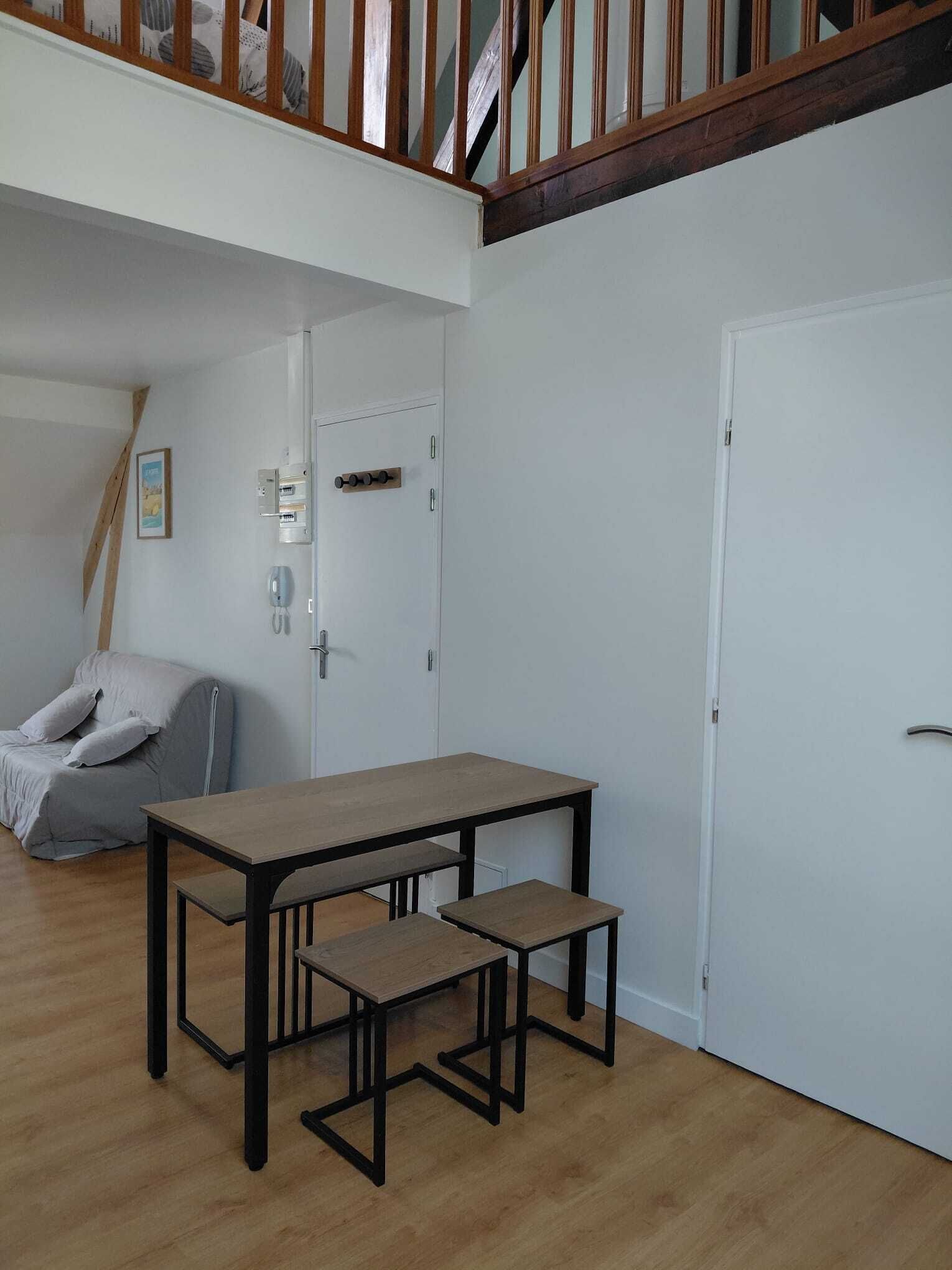 Ein Zimmer mit einem Holztisch, einer Bank, einer weißen Tür und einem grauen Stuhl.