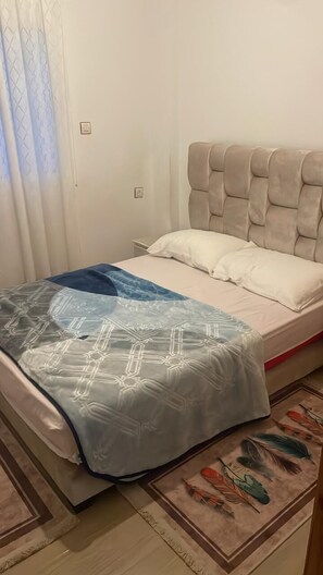 Un lit avec une tête de lit, une couverture et un coussin décoratif.